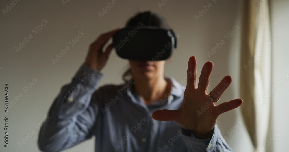An young happy woman is using innovative technology vr glasses for play games and relax herself after hard working day. Concept of future, innovation, technology, gaming,lifestyle, entertainment