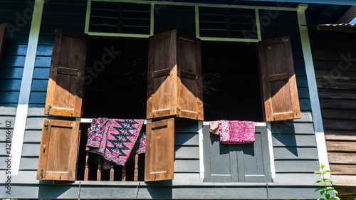 Batik fabric hanging on the window of Rumah Kampung under the bright sunlight. photo