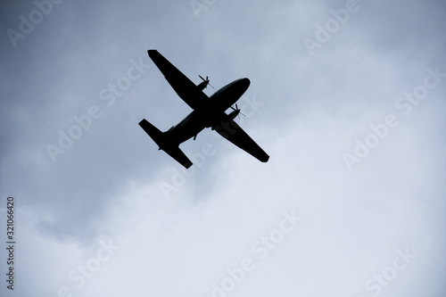 Silhouette two engine propeller airplane on sky, photoshoot from under while plane flying.