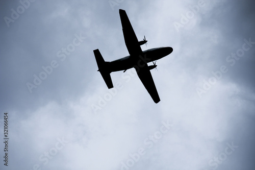 Silhouette two engine propeller airplane on sky, photoshoot from under while plane flying.