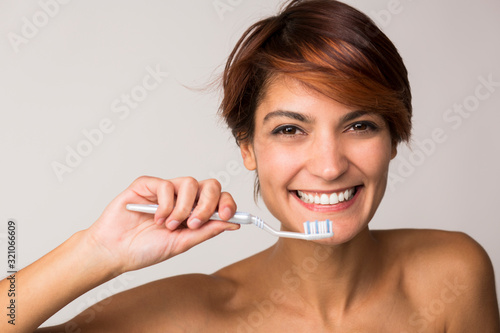 Foto bella ragazza con i capelli corti è felice di lavarsi i denti, isolata su sfondo