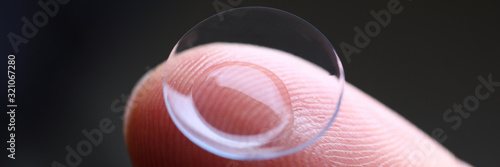 Human finger holding soft contact lens