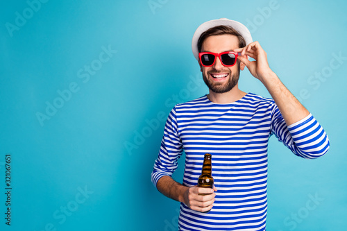 Photo of nice traveler guy drink beer bottle all inclusive exotic resort good mood summer holidays wear sun specs striped sailor shirt cap isolated blue color background