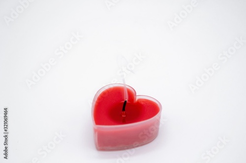 A red heart-shaped candle extinguished on a white background. Copy space. Concept of love, Valentine's Day, end of relationship