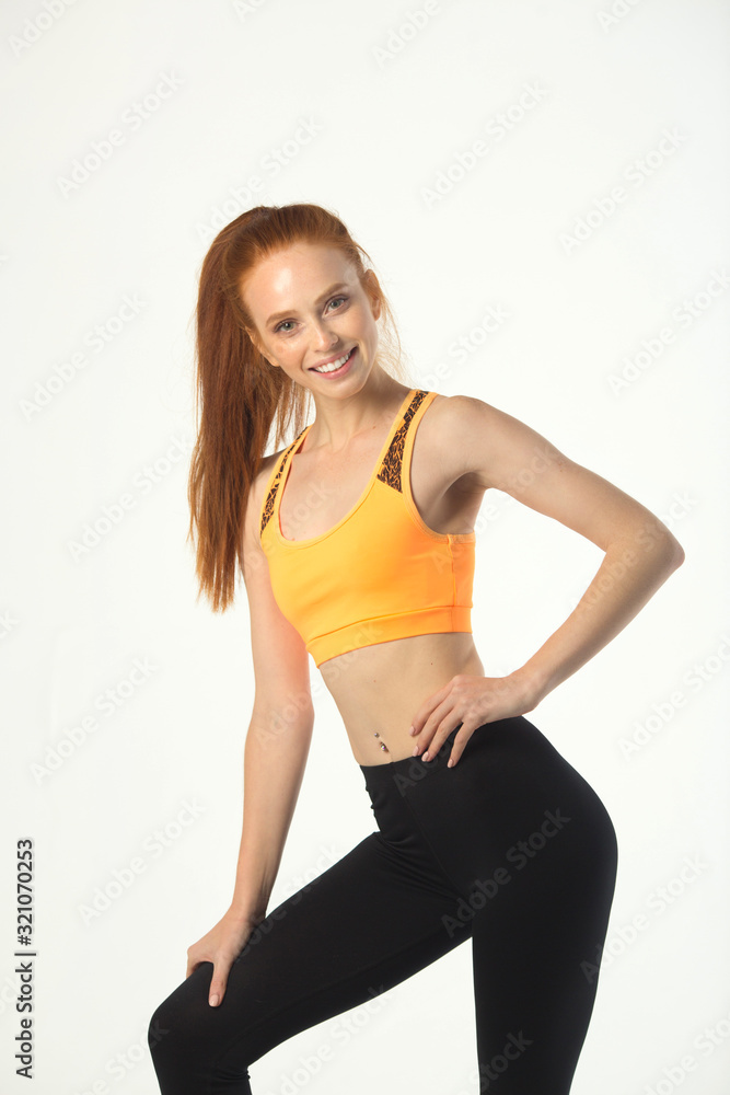 beautiful young slim woman with red hair in sportswear on a white background
