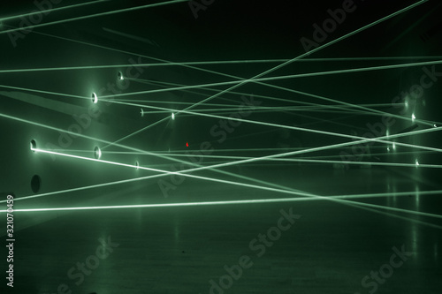 Green laser beams in a chaotic order from one wall to another.  Safety system