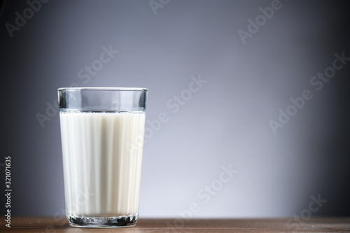 Glass faceted cup with milk stands on a wooden table 