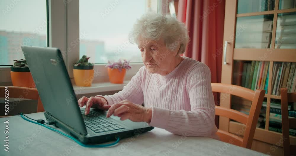 Grandmotehr sitting in front of her laptop and browsing the internet Grandmotehr sitting in front of her laptop and browsing the internet
