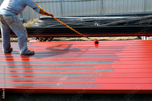 worker man rustproof paint red color on steel by use long rolling tool working.
