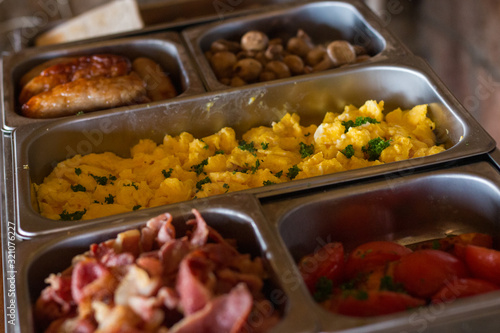 South African breakfast with scrambled eggs, bacon, pork sausages and mushrooms