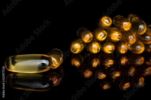 Lot of whole arranged golden fish oil isolated on black glass