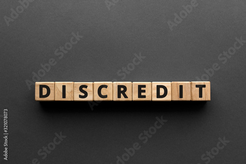 Discredit - words from wooden blocks with letters, loss of reputation or respect discredit concept, top view gray background photo