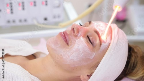 Receiving electric darsonval facial massage procedure.