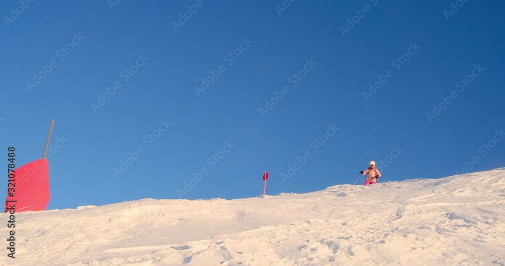 Woman skier going off-piste over a ridge next to a ski slope on the Sella ronda ski tour in Dolomites mountains, Italy - tracking shot. Woman skier going off-piste over a ridge next to a ski slope on the Sella ronda ski tour in Dolomites mountains, Italy - tracking shot.
