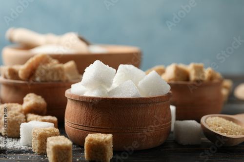 Bowls with different sugar on wooden background, close up