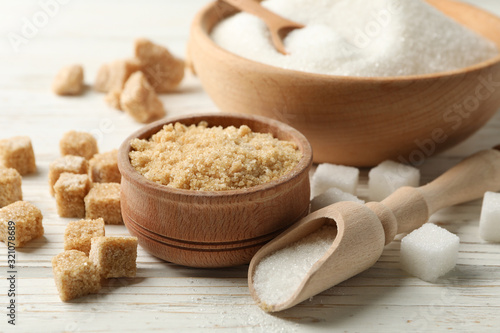 Bowls with sugar on white wooden background, close up