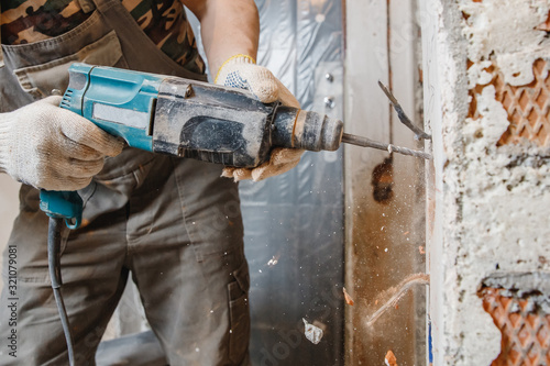 Foto Builder worker pneumatic hammer drills hole in concrete brick wall with diamond