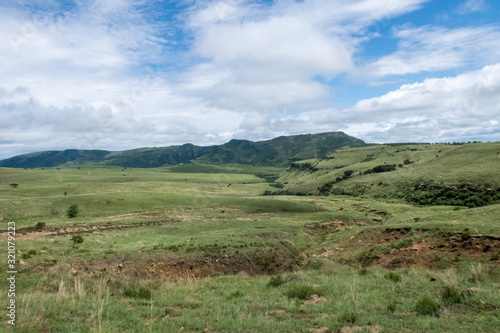 Wide open green fields with bright blue sky and white clouds in the Drakensberg Mountains in South Africa
