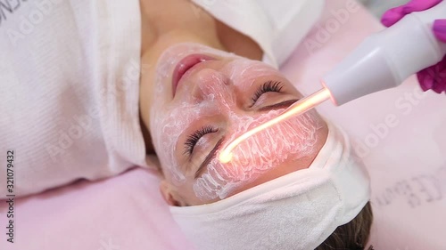 Receiving electric darsonval facial massage procedure.