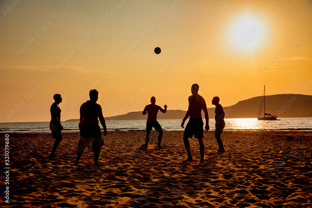 A game of football on the beach at sunset