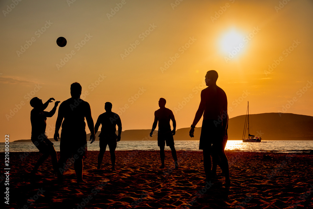 A game of football on the beach at sunset