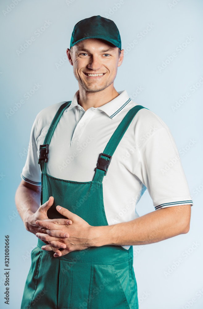 Portrait of young worker man wearing green uniform with crossing hands. Isolated on grey background with copy space. Human face expression, emotion. Business concept. Portrait of young worker man wearing green uniform with crossing hands. Isolated on grey background with copy space. Human face expression, emotion. Business concept.
