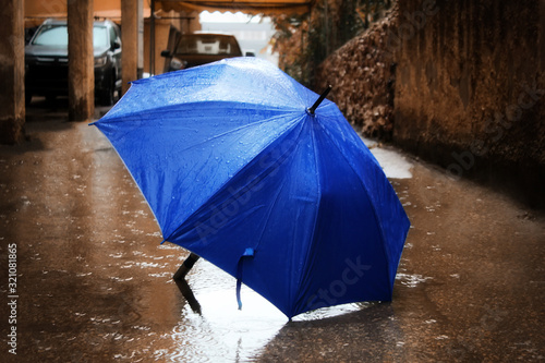 Winter in Israel, Rain, Flood, rainy weather. Umbrella with raindrops in a big puddle