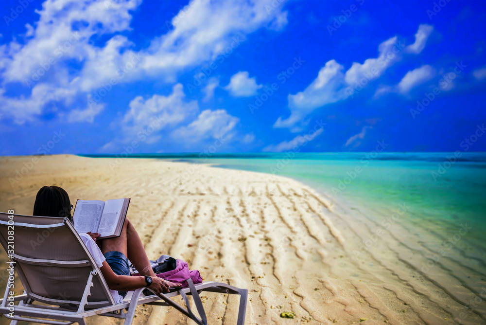 Young woman sitting on deck chair at tropical beach reading book holiday vacation . Young woman sitting on deck chair at tropical beach reading book holiday vacation .