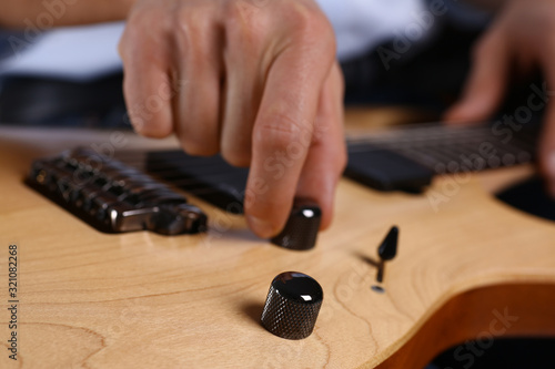 Male arms holding and playing classic shape wooden electric guitar closeup. Six stringed learning musical school education art leisure electrical vintage stage shop having fun enjoying hobby concept