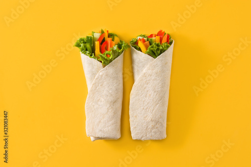 Vegetable tortilla wraps on yellow background. Top view
