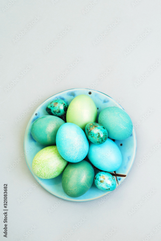 Bright multi-colored Easter eggs in a plate on a gray background, top view. Easter background. Bright multi-colored Easter eggs in a plate on a gray background, top view. Easter background.
