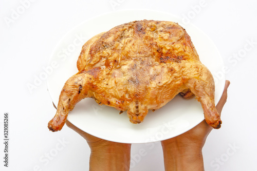 hands holding whole chicken on a plate isolated on white photo