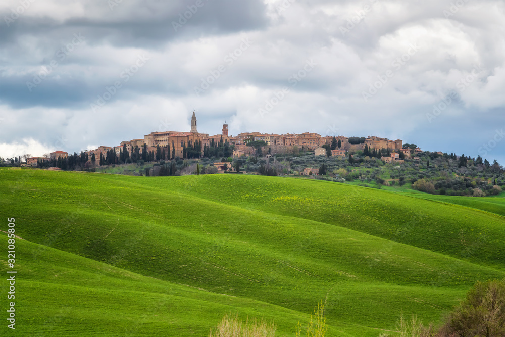 Amazing spring landscape with green rolling hills and old town of Pienza in the distance, Tuscany, Italy