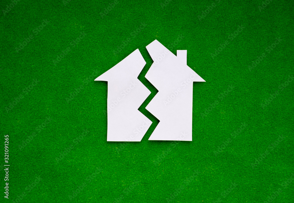two halves of the house made of white paper on a green background. the concept of property, the real estate market.