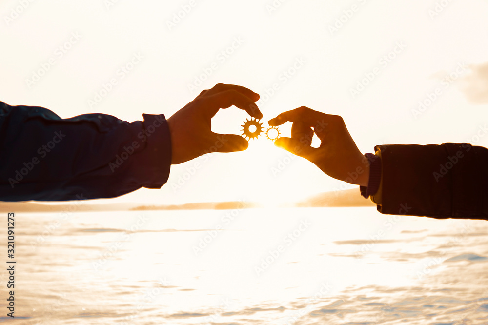 Two gears in the hands of people on the background of the winter landscape.
