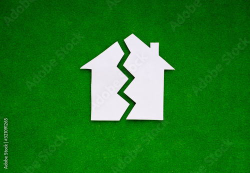 Obraz na płótnie two halves of the house made of white paper on a green background. the concept of property, the real estate market. w salonie