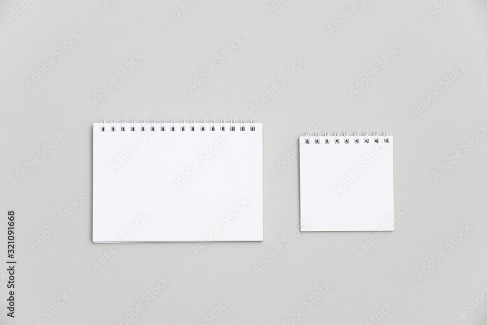 Two blank notepads on gray background to replace your design. Top view mockup. Two blank notepads on gray background to replace your design. Top view mockup.