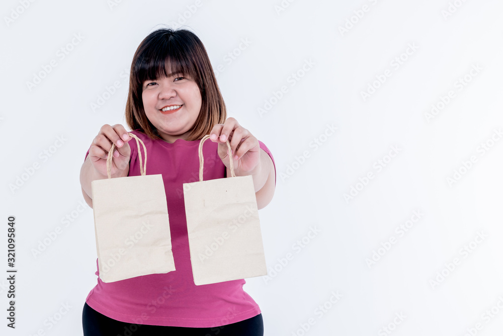Portrait images of Asian fat woman standing and Holding a paper bag on white background, concept to Global warming reduction campaign By using paper bag replacement plastic bag Portrait images of Asian fat woman standing and Holding a paper bag on white background, concept to Global warming reduction campaign By using paper bag replacement plastic bag