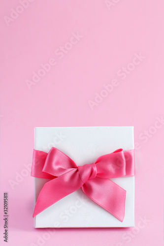 White gift box with a bow on a light pink background © katrinshine