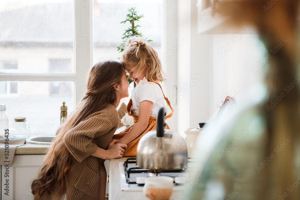 Two sisters play in a bright, stylish kitchen. Beautiful interior. - obrazy, fototapety, plakaty 