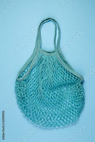Blue cotton mesh bag on blue paper background. Reusable shopping bag on color background. Ecological, Zero waste concept. Top view, flat lay, copy space