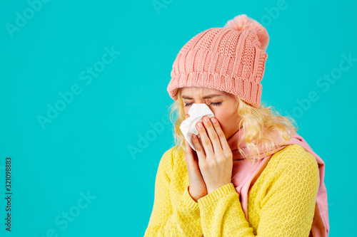 Cold and flu season- portrait of a woman in hat and scarf blowing her nose photo