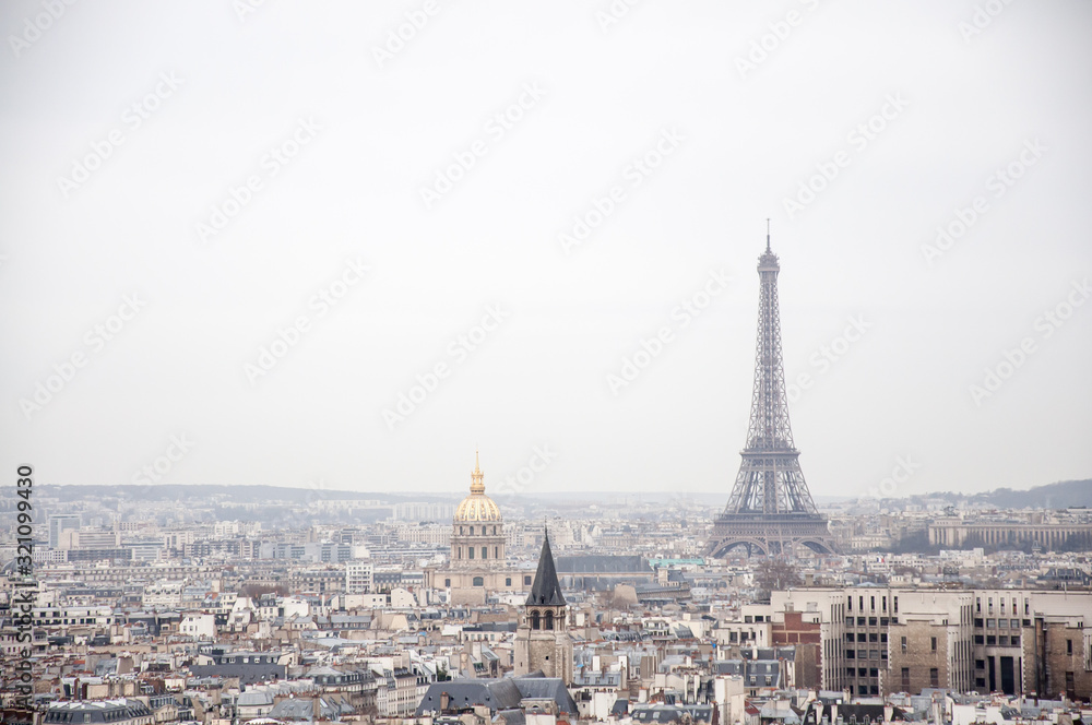 Scenic view over the Paris roofs with Eiffel Tower in background on a hazy day with the overcast sky.