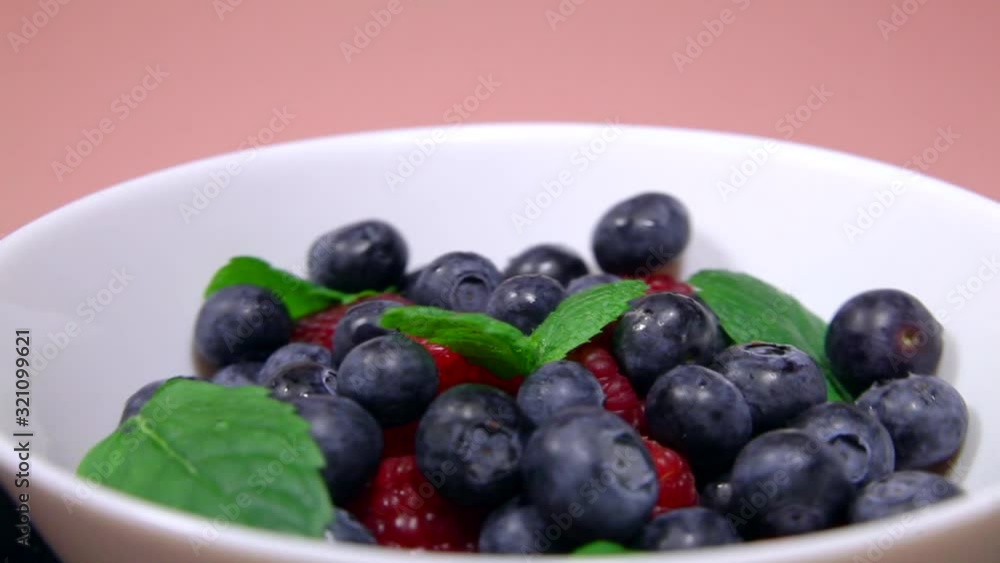 Blueberries and raspberries in a plate with mint petals, forgiveness in a circle. Blueberries and raspberries in a plate with mint petals, forgiveness in a circle.