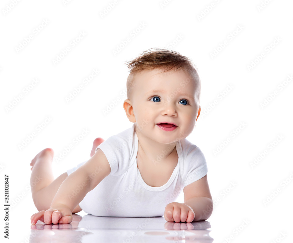 Happy smiling infant child baby boy toddler with blue eyes in white t-shirt is lying on his stomach crawling on white Happy smiling infant child baby boy toddler with blue eyes in white t-shirt is lying on his stomach crawling on white
