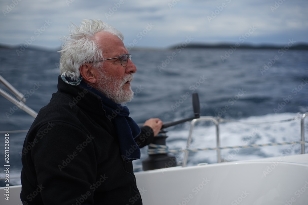 White bearded sailing senior, experienced skipper on a sailboat White bearded sailing senior, experienced skipper on a sailboat