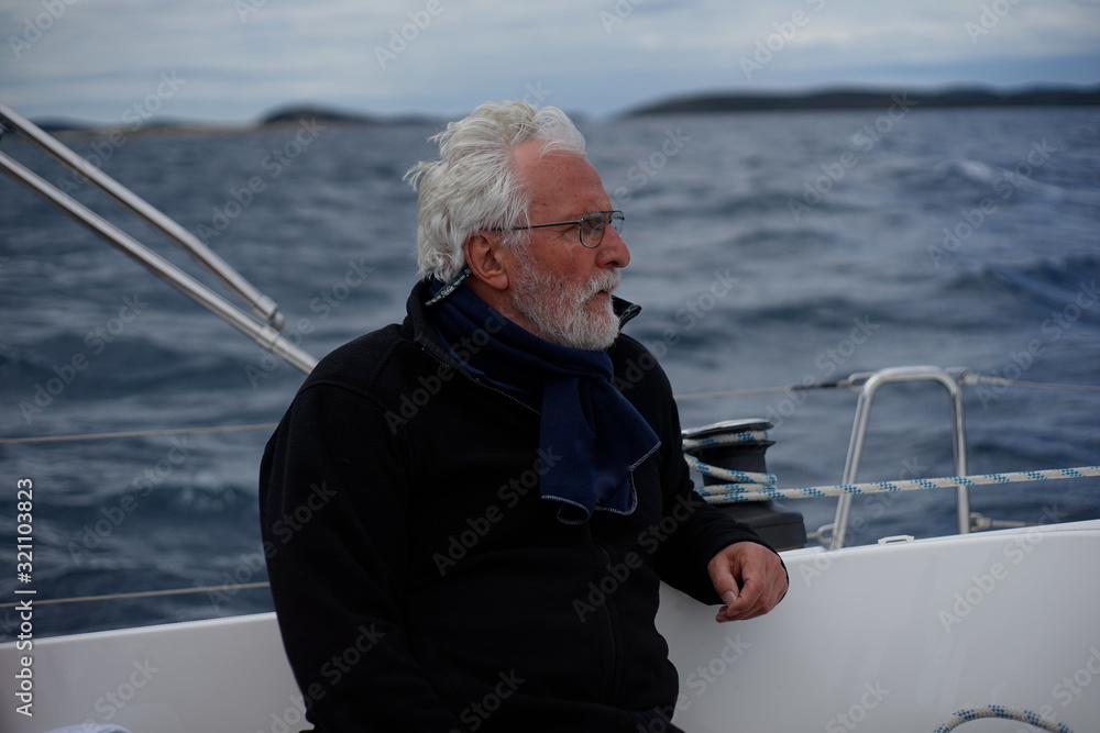 White bearded sailing senior, experienced skipper on a sailboat White bearded sailing senior, experienced skipper on a sailboat