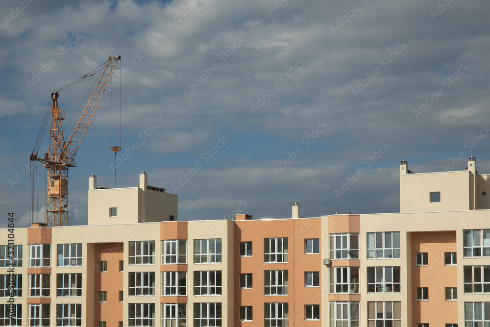 Construction site with cranes and building with cloudy sky background