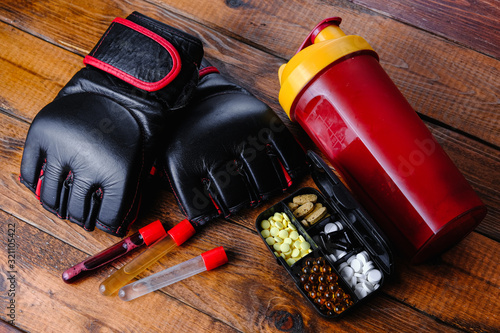 mma gloves and steroid medication with sport nutrition composition on a wooden background