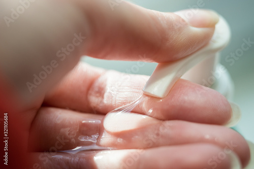 Female hand push on soap dispenser bottle close-up.